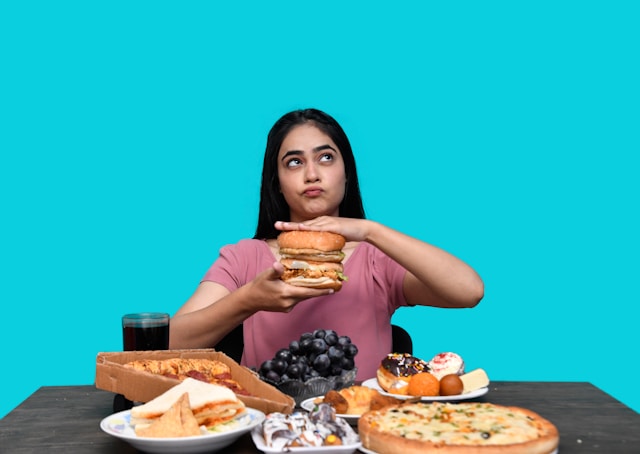 Compulsão alimentar de uma menina com várias comidas na mesa.