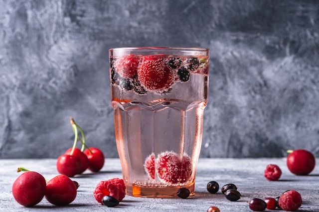 Água saborizada com frutas vermelhas no copo